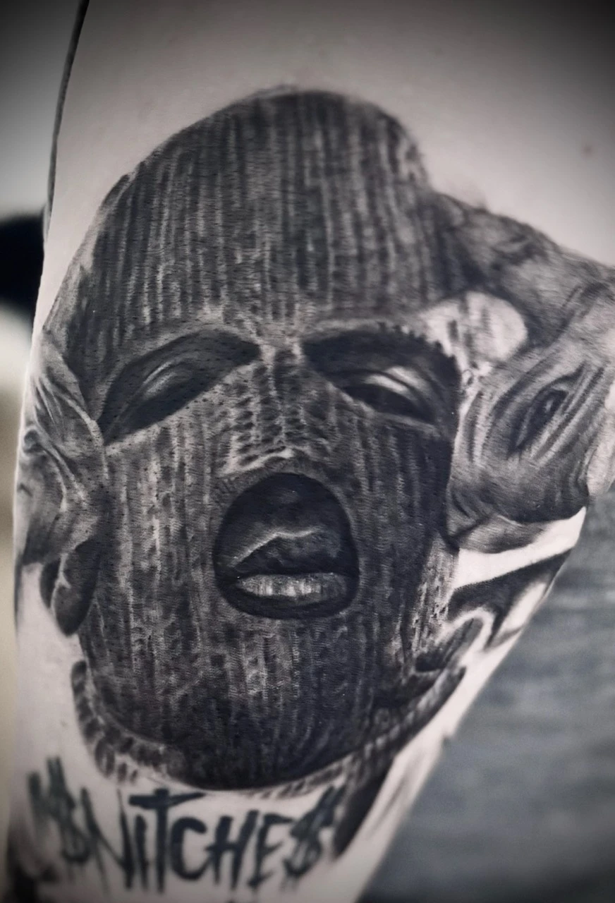 Sehr realistische Darstellung eines Mannes mit Maske als Tattoo auf der Schulter, gestochen von ON Tattoo Artist Freiburg, Ton und Tinte.